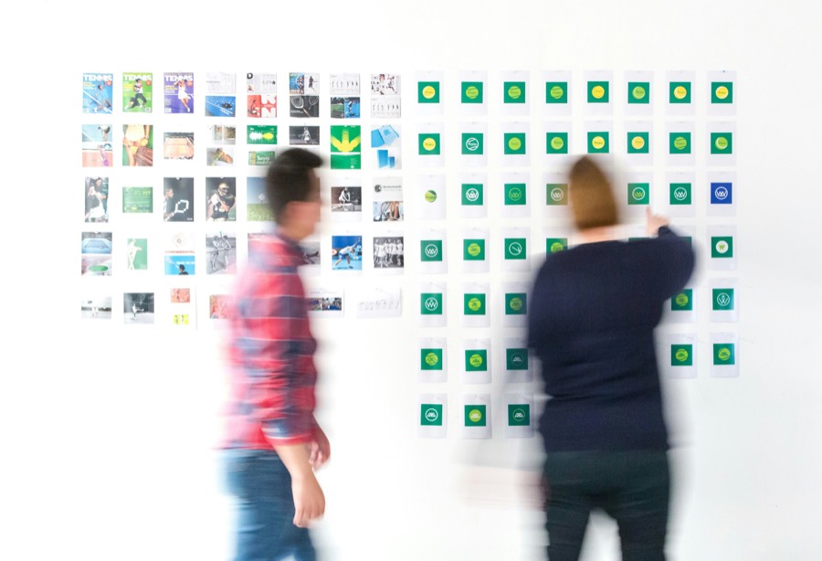 Two people planning a campaign on a wall of printed concepts
