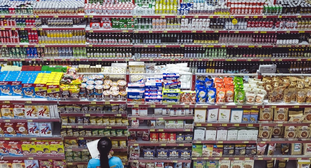 Grocery store worker carrying a crate of tomatoes